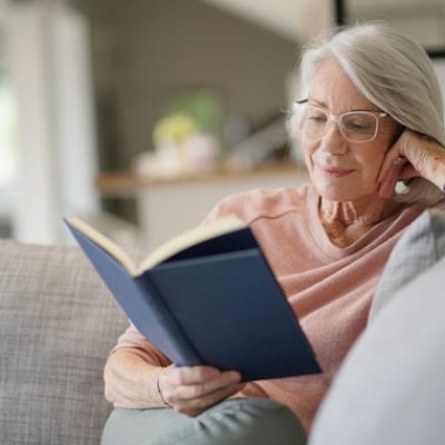 Senior woman reading on couch at home